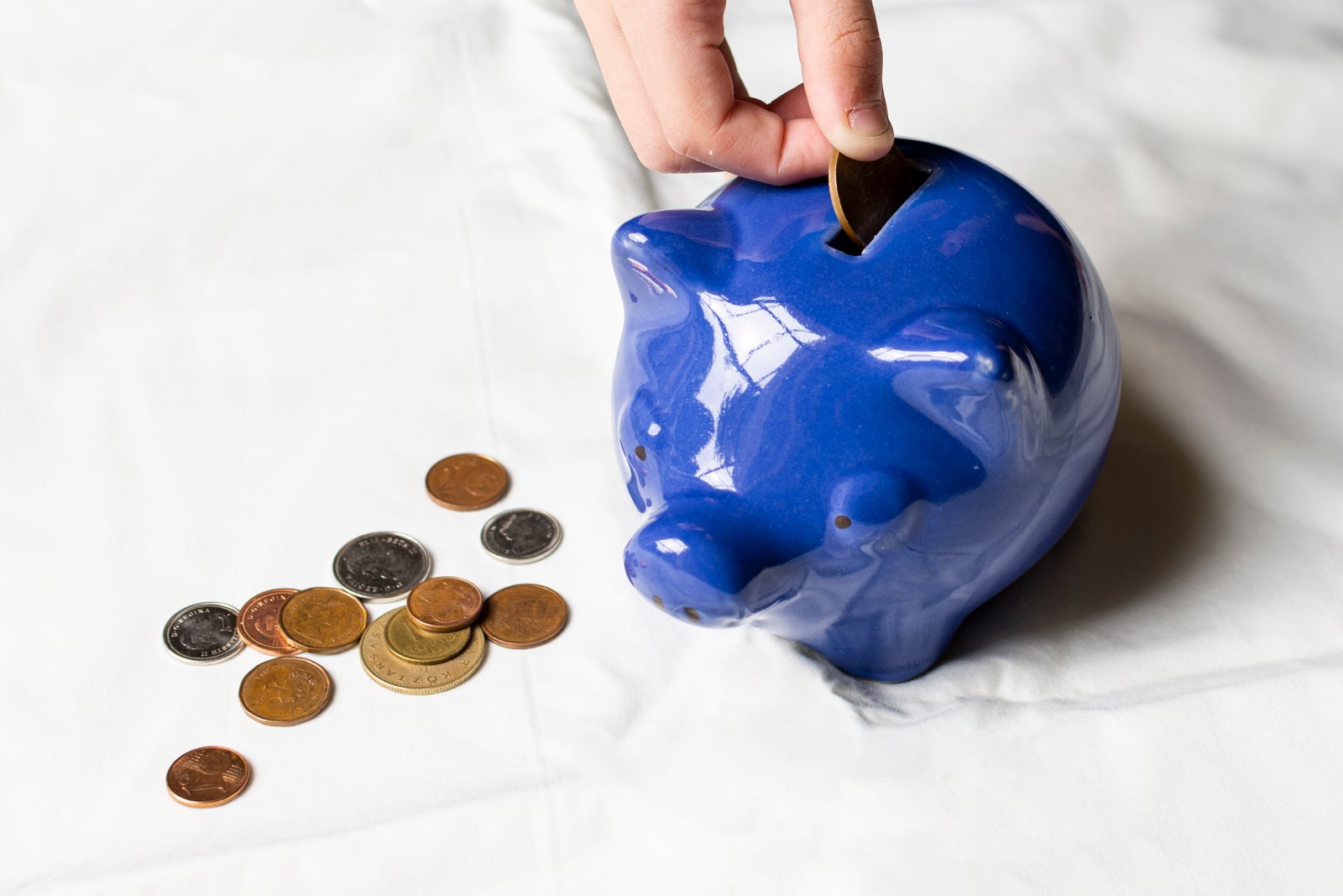 Persona echando monedas a una hucha azul